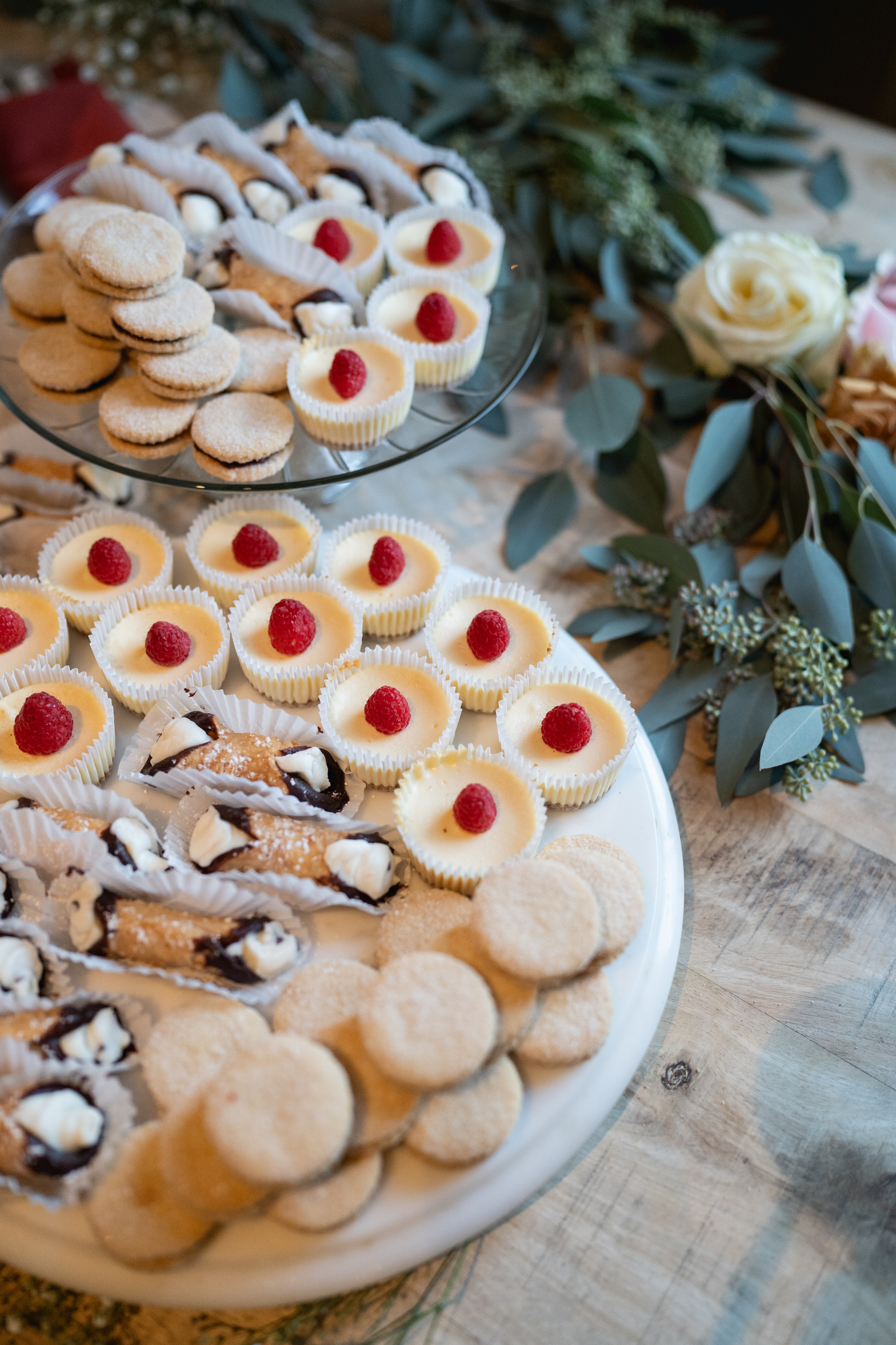 Dessert display table at a wedding reception with cannoli and mini cheesecakes